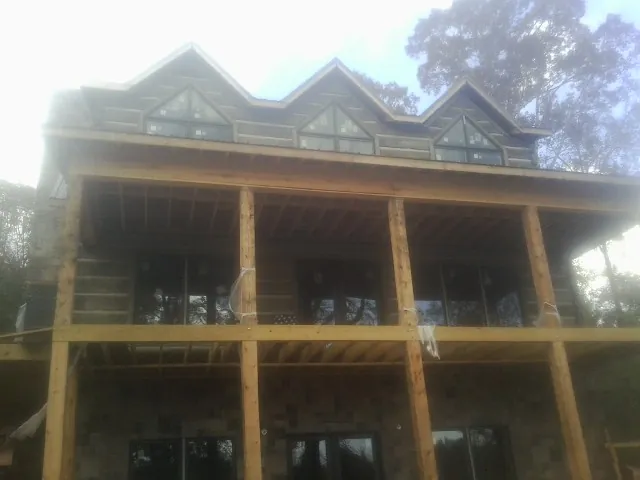 Dormers and porch framing on a large log home under construction — Roof Coating work by our crew in Houston